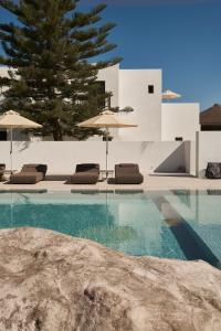a swimming pool with lounge chairs and umbrellas at Parilio, a Member of Design Hotels in Naousa