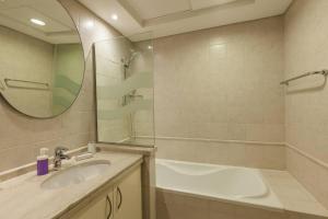 a bathroom with a sink and a tub and a mirror at Houst Holiday Homes - Green Commnity West in Dubai