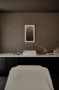 a bedroom with a white bed and a sink at Parilio, a Member of Design Hotels in Naousa