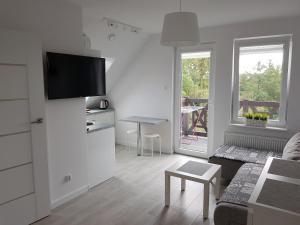 een witte woonkamer met een tv aan de muur bij Sztutowo Apartament Jaś in Sztutowo