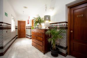 a hallway with a wooden dresser and potted plants at Hostal La Muralla in Seville