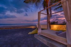 a room with a hammock on the beach at sunset at Kutus Kutus Saba Beach Villa in Gianyar