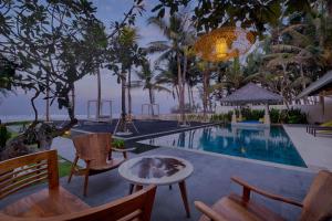 a swimming pool with chairs and a table next to a resort at Kutus Kutus Saba Beach Villa in Gianyar