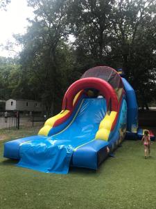 a little girl is standing in front of a bouncy house at Particulier loue mobil-home dans le parc siblu in Saint-Brevin-les-Pins