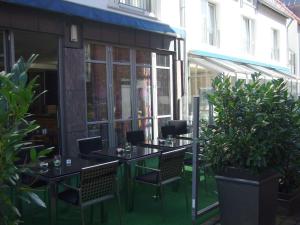 a patio with two tables and chairs and plants at Sporthotel Wiedenbrueck in Rheda-Wiedenbrück