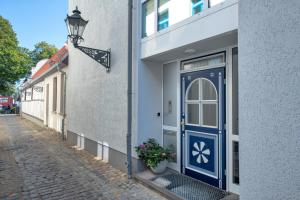 eine blaue Tür in einem weißen Gebäude mit Straßenlicht in der Unterkunft Pension StromInn in Warnemünde