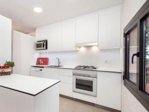 a white kitchen with white cabinets and appliances at Holiday Home Paris by Interhome in Calonge