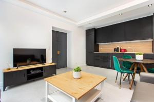 a living room with a table and a kitchen with black cabinets at CMG Parc de Bercy - Madagascar in Paris