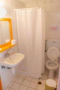 ZagaMilos Hotel في كوروني: حمام مع ستارة دش بيضاء ومرحاض