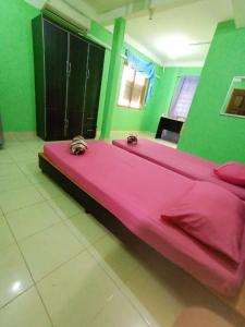 a large pink bed in a room with green walls at DAOH'S Rooms & Scooters in Tanjung Rhu