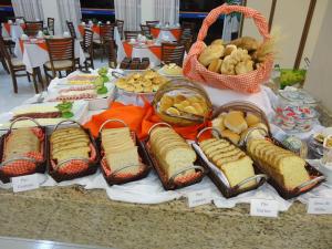 ein Tisch mit Sandwiches und anderen Speisen darauf in der Unterkunft Hotel Dom Baroni in Guarapuava