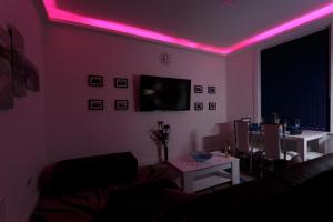 ein Wohnzimmer mit rosa Lichtern an der Decke in der Unterkunft Clifton Bespoke Serviced Apartments in Leeds