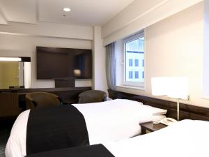 APA Hotel Akasaka-Mitsuke في طوكيو: غرفة فندقية بسريرين وتلفزيون بشاشة مسطحة