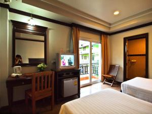 um quarto de hotel com uma cama e uma secretária com uma televisão em P.P. Casita - Adult Only em Phi Phi Don