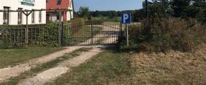 a gate with a parking sign next to a road at Hotel Kranichblick in Kluis