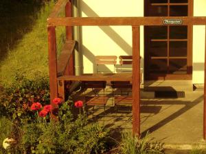 un porche de madera con un banco y flores en Hotel Kranichblick, en Kluis