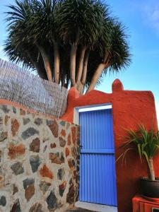 a blue door in a red wall with palm trees at Vivelorural casa La Cuevita, Santa Brígida in Santa Brígida +33 photos