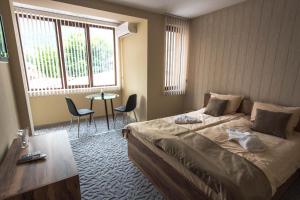 a bedroom with a bed and a table and chairs at Etobicoke -Стаи за гости in Etropole