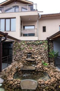a house with a stone wall with a water fountain at Etobicoke -Стаи за гости in Etropole +15 photos