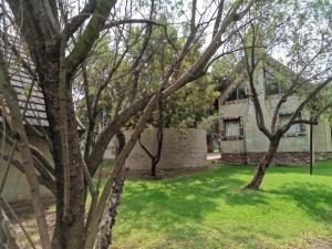 una casa con un patio verde con árboles en Umuzi Lodge en Secunda