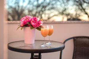 un tavolo con due bicchieri e un vaso di fiori rosa di LAMALU a Ližnjan (Lisignano)