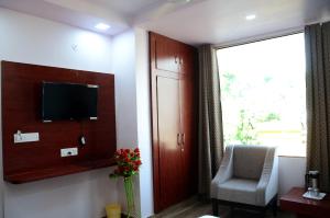 um quarto com uma televisão, uma cadeira e uma janela em Meera Mahal em Sawai Madhopur