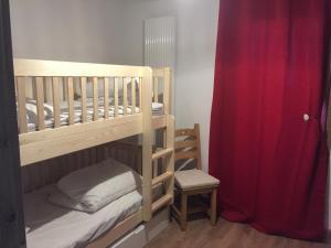 een slaapkamer met 2 stapelbedden en een rood gordijn bij les 7 laux immobilier chalet E in Prapoutel