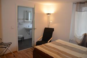 a bedroom with a bed and a chair and a bathroom at Pension Laabs in Schönefeld