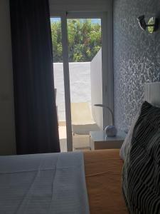 a bedroom with a bed and a window with a chair at Rainbow Golf Bungalows, Gay Men-only Resort in Maspalomas