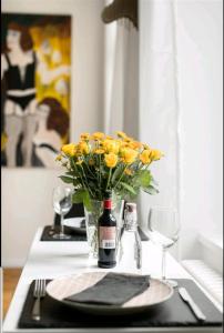 un tavolo con una bottiglia di vino e un vaso di fiori gialli di Kleinod am Park - Zentrum-Südost a Lipsia