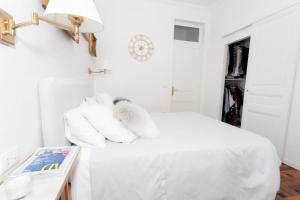 een witte slaapkamer met witte kussens op een bed bij Charmant 2 pieces frontiere Monaco in Beausoleil