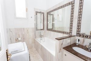 een badkamer met een bad, een wastafel en een spiegel bij Charmant 2 pieces frontiere Monaco in Beausoleil