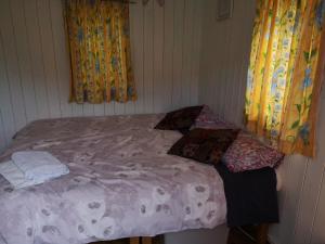 a small bed in a room with curtains at Stybeck Farm Shephards Hut in Thirlmere