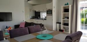 a living room with a dining table and a kitchen at De Zeeuwse Lûûkjes 1 in Serooskerke
