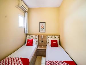 2 Betten in einem kleinen Zimmer mit roten Kissen in der Unterkunft OYO Hotel Itarantim, São Paulo in São Paulo