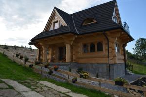 uma cabana de madeira com um telhado preto em Osada Witów - dom "Miłosna Górska" em Witów