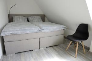 a bed and a black chair in a room at Deck 3 Laboe Ostsee in Laboe