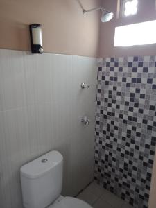 baño con aseo y pared de azulejos en JOGLOPARI GuestHouse bukan untuk pasangan non pasutri, en Bantul