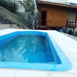 uma piscina em frente a um chalé de madeira em Cabañas Rosaverde em Alto La Viña