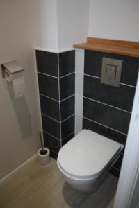 een badkamer met een wit toilet en een muur met zwarte tegels bij L'ALBATROS in Granville