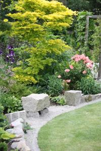 un giardino con panca in pietra e fiori di Apartment in the countryside in Tossene Hunnebostrand a Hunnebostrand