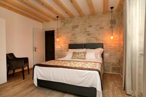 a bedroom with a bed and a stone wall at Villa Teuta in Trogir