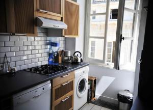 a kitchen with a stove and a washing machine at Burdigala Homes - Appart Sainte Catherine in Bordeaux