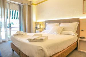 una camera da letto con un grande letto bianco con asciugamani di Hotel Augustus a Fano