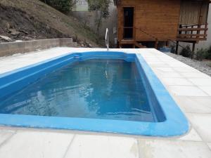 uma piscina azul num quintal com uma casa em Cabañas Rosaverde em Alto La Viña