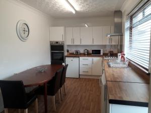cocina con armarios blancos y mesa de madera en Hilltop House en Airdrie