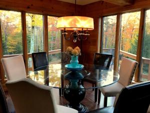 a dining room with a glass table and chairs at Mink Hollow Lodge in Elka Park
