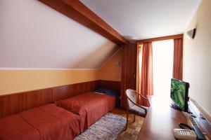 Schlafzimmer mit einem Bett, einem Schreibtisch und einem TV in der Unterkunft Gostišče Prosnik in Ormoz