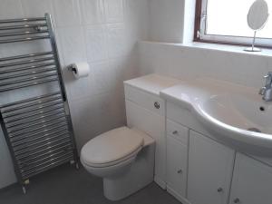 Baño blanco con aseo y lavamanos en Hilltop House en Airdrie