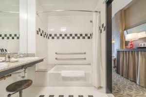 a white bathroom with a tub and a sink at Proximity Hotel in Greensboro